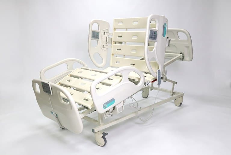 F5 Medical Bed, three-quarter view with backrest and knee section raised, bare deck, rails up
