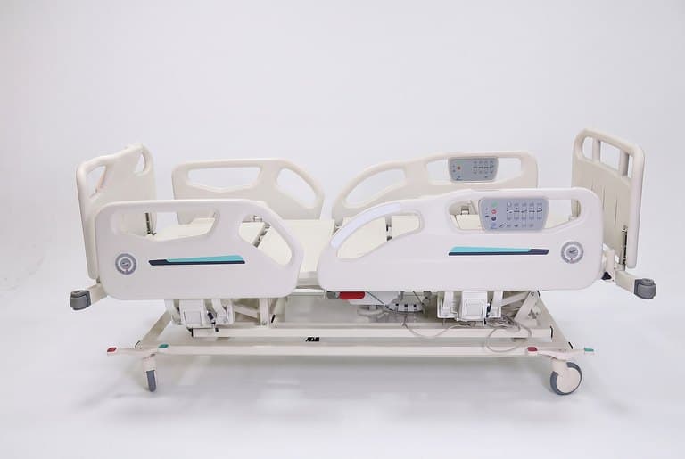 Santron Pro ICU Bed, side view flat with split side rails raised and rail control panels, white studio