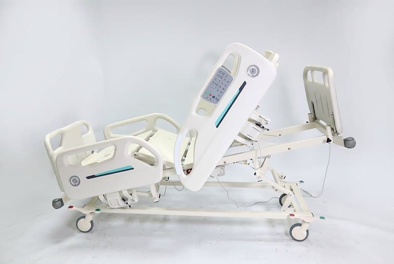 Santron Hospital Bed, side view with backrest raised upright, rail control panel visible, white studio